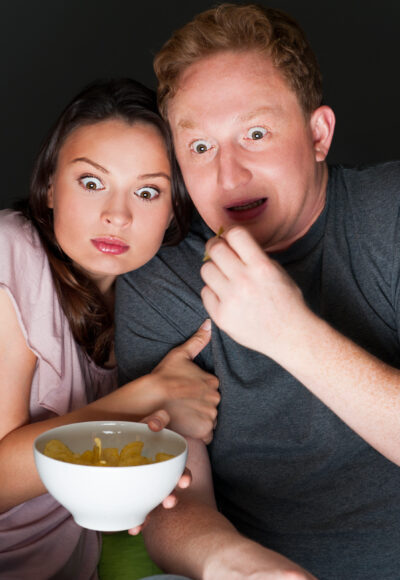 A couple watching a scary movie and it scared them so much that they are screaming.