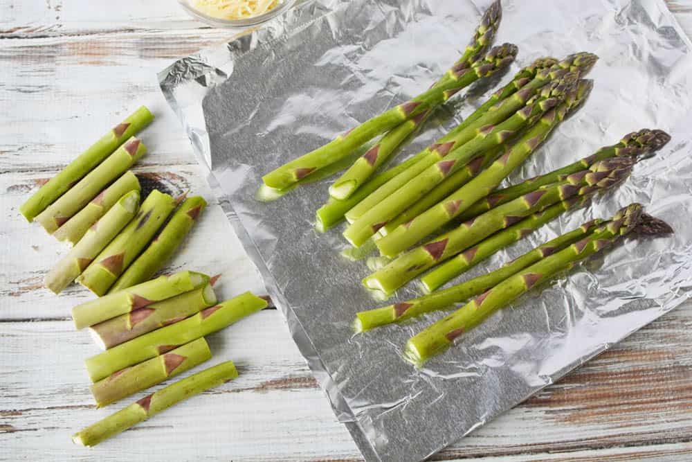 Fresh asparagus on piece of foil with ends trimmed off.