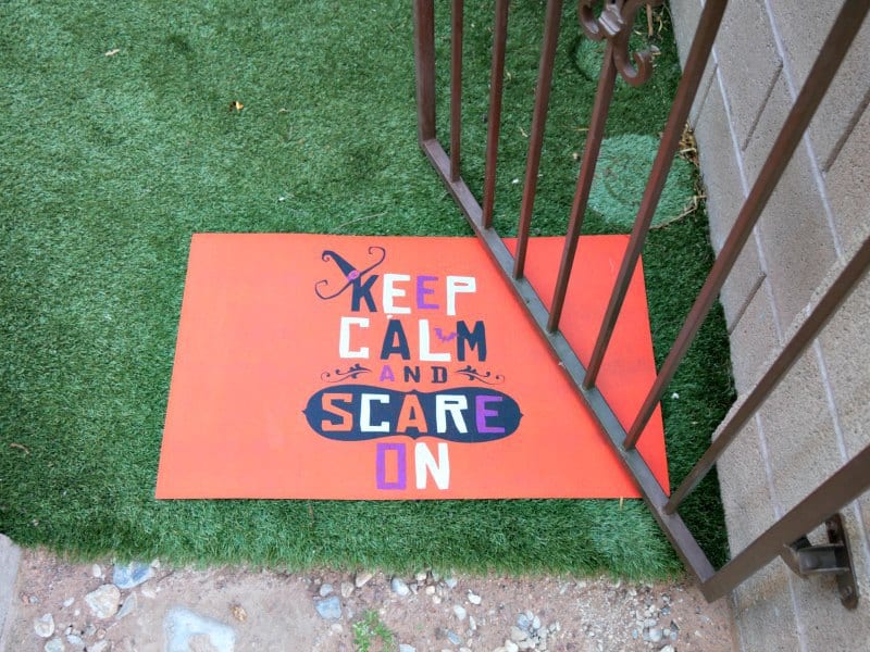Keep calm and scare on doormat at a backyard gate