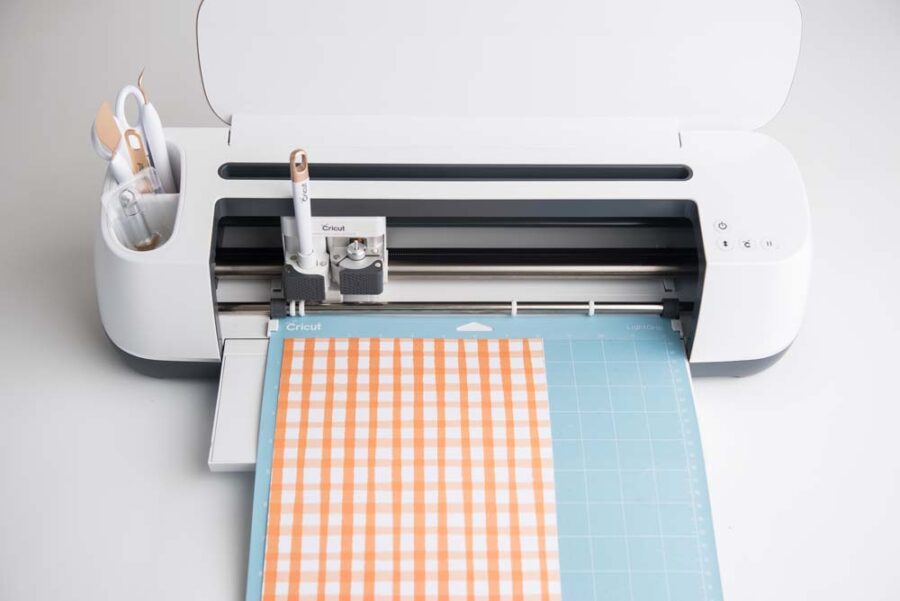 Orange and white checked cardstock on blue mat in Cricut Maker
