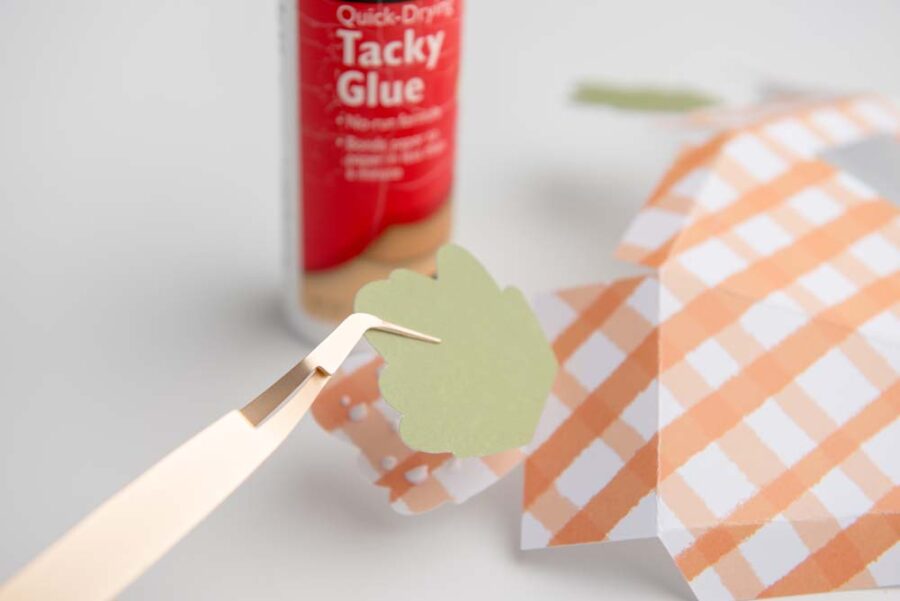 Green leaf being glued onto carrot box top