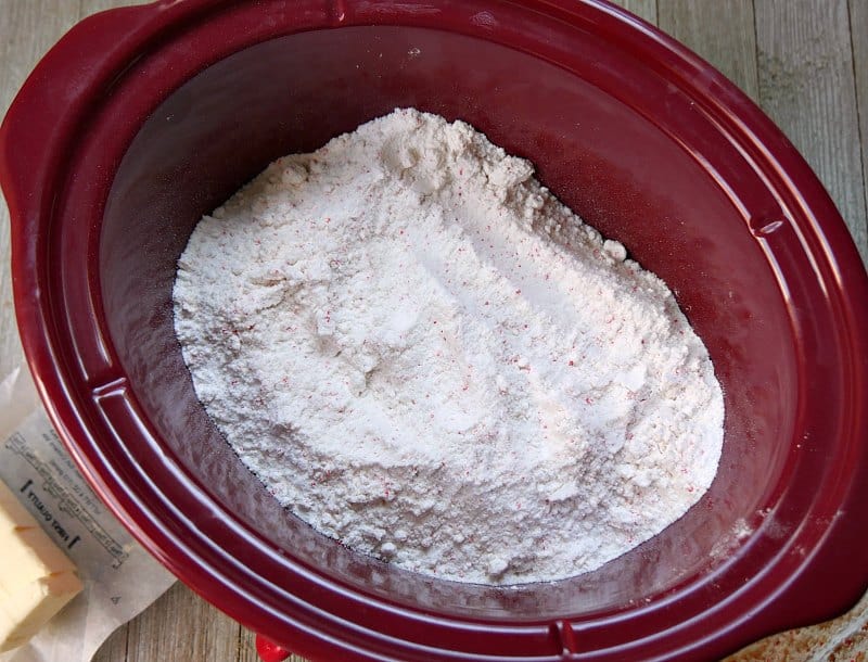 Red oval slow cooker with cherry chip cake mix in it