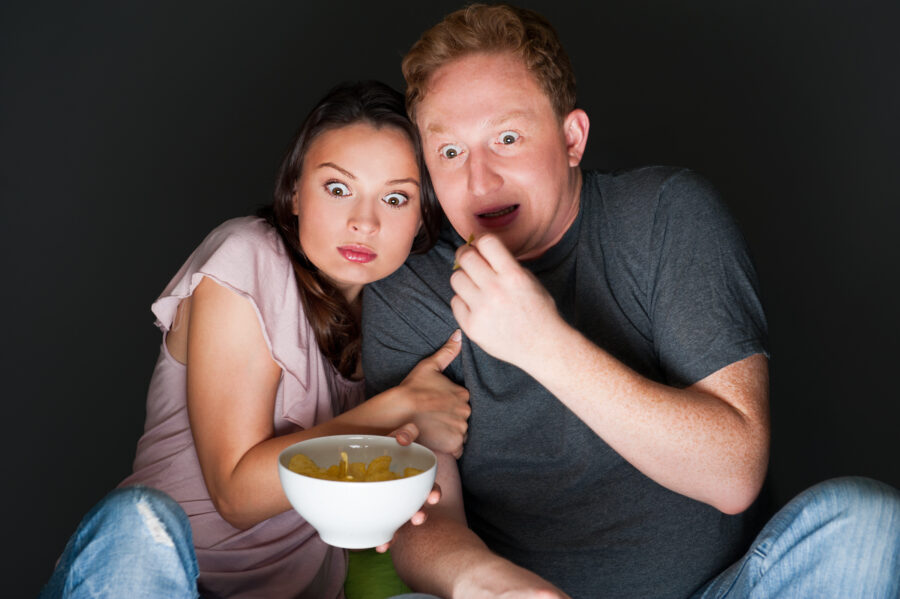 A couple watching a scary movie and it scared them so much that they are screaming.