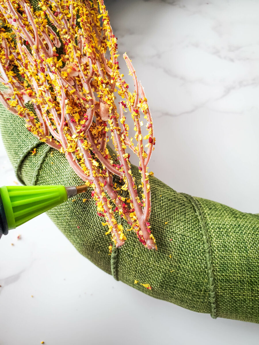 Hot glue gun with the floral decorations on the gnome wreath