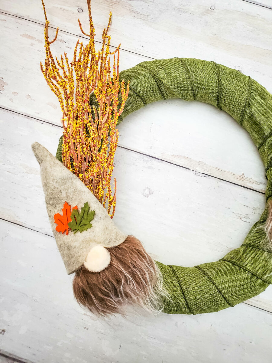 A gnome glued over the floral decorations on the wreath