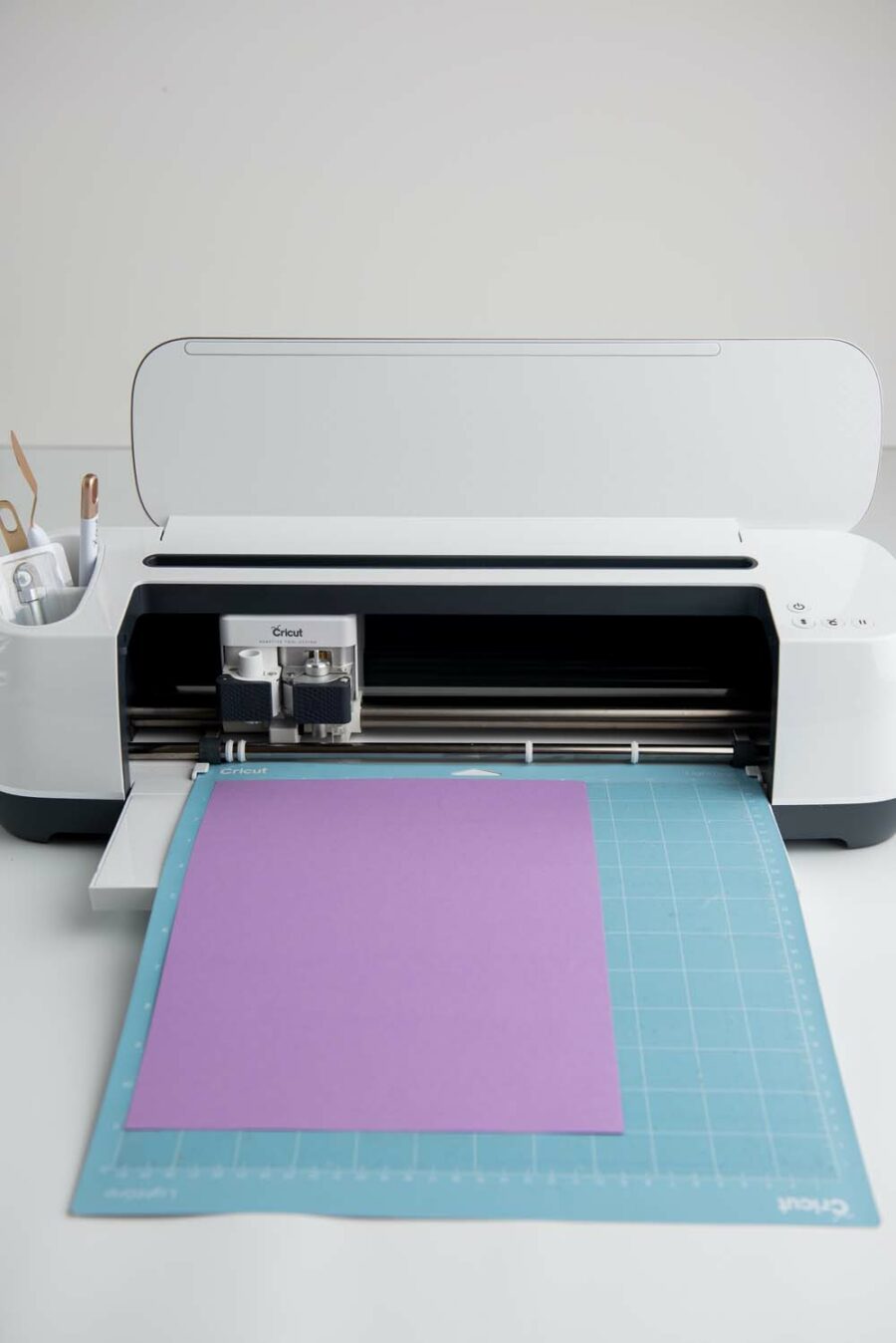 Cricut maker with purple card stock on a blue mat