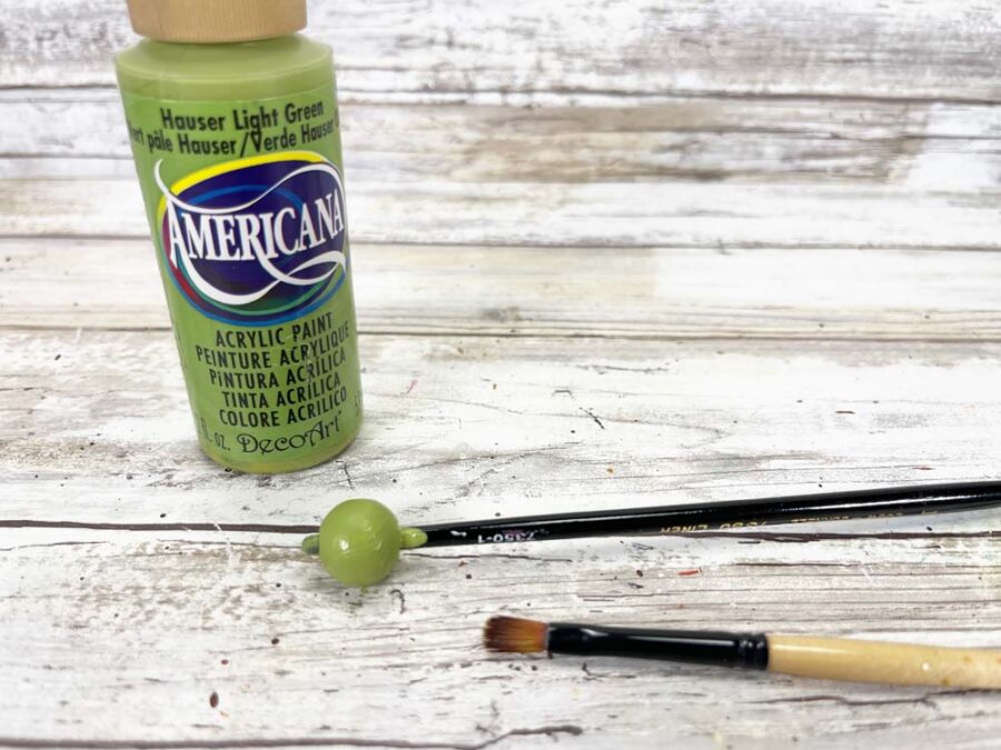 Small wood bead painted green, green paint, paint brush
