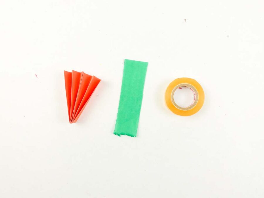 Orange accordion carrot, green tissue paper and a roll of tape