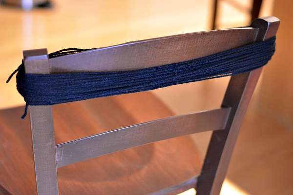 Black yarn used to make a yarn spider wrapped around a chair.