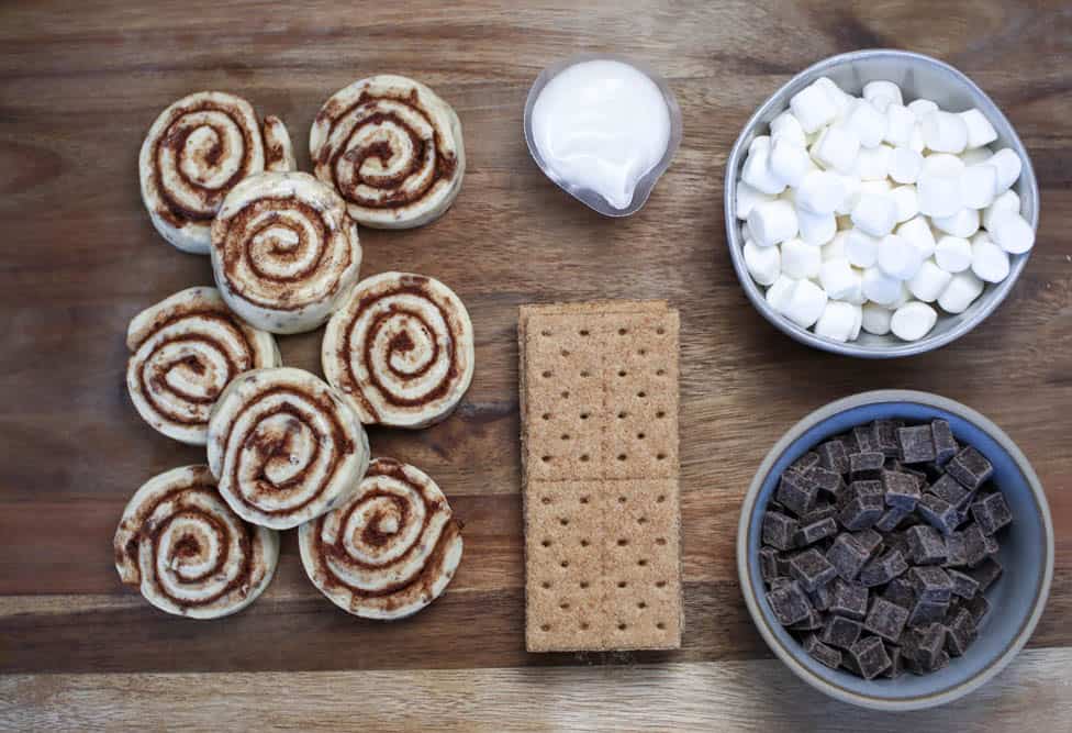 Ingredients to make s'mores monkey bread: cinnamon rolls, graham crackers, frosting, marshmallow and chocolate chunks 