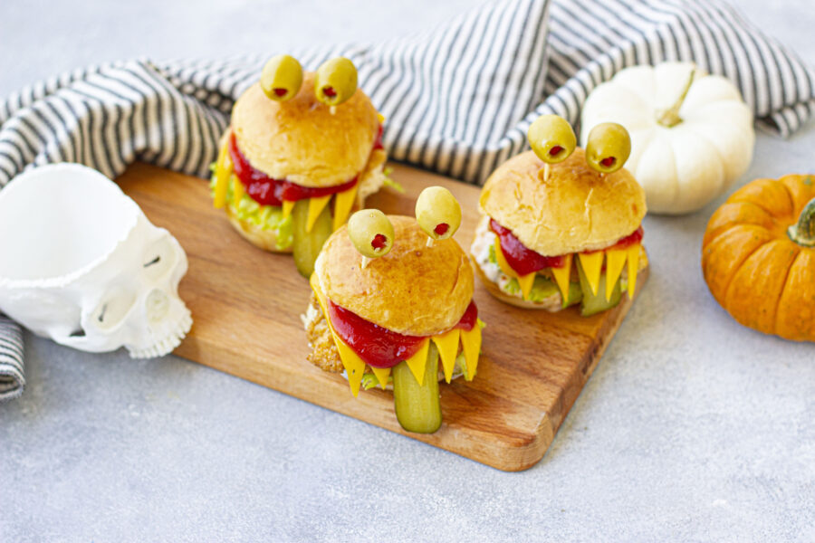 three monster burgers on a cutting board
