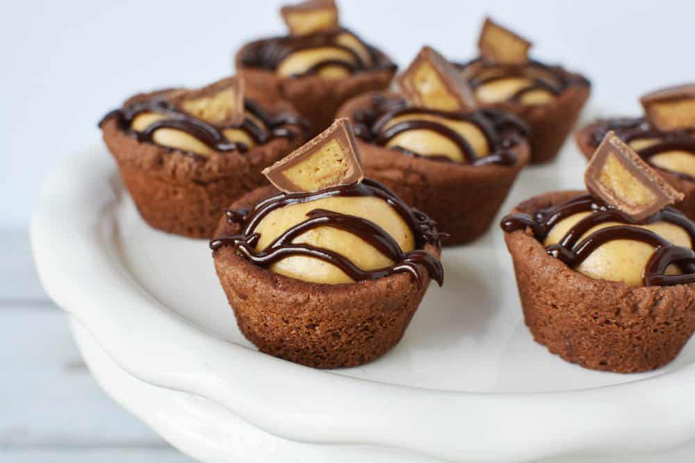chocolate peanut butter cookie cups with candy on top on white platter 