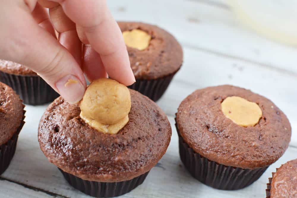 Topping the chocolate cupcakes with peanut butter