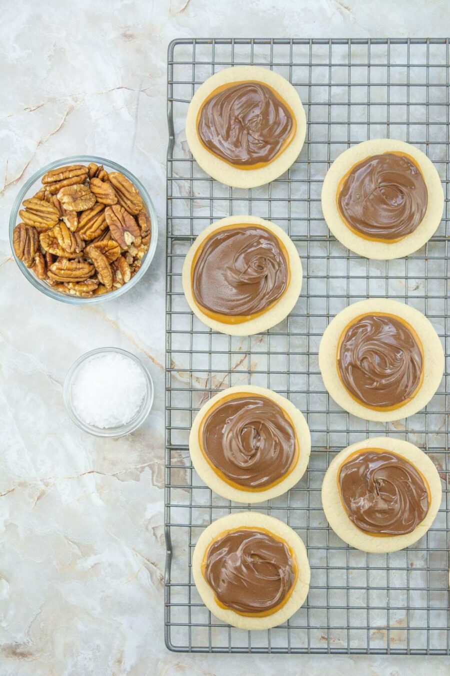 Baked pecan turtle cookies with bowl of pecans and salt on the side