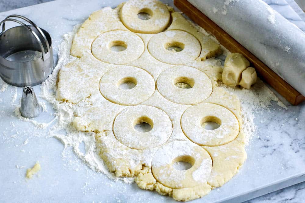 Donut dough rolled out and cut with a donut cutter
