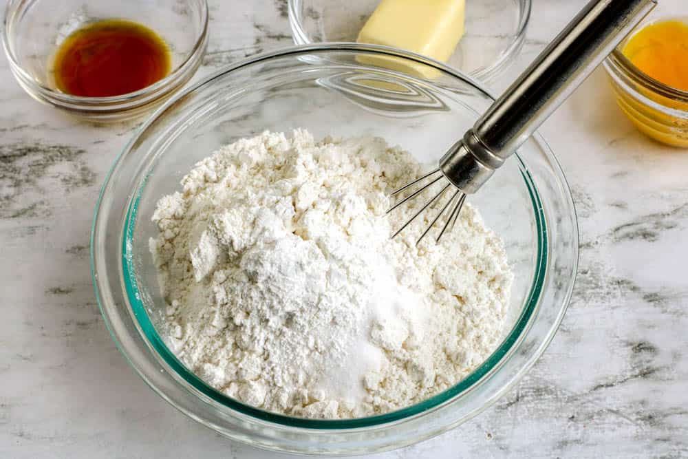 Dry ingredients for making donuts in a bowl with a whisk.