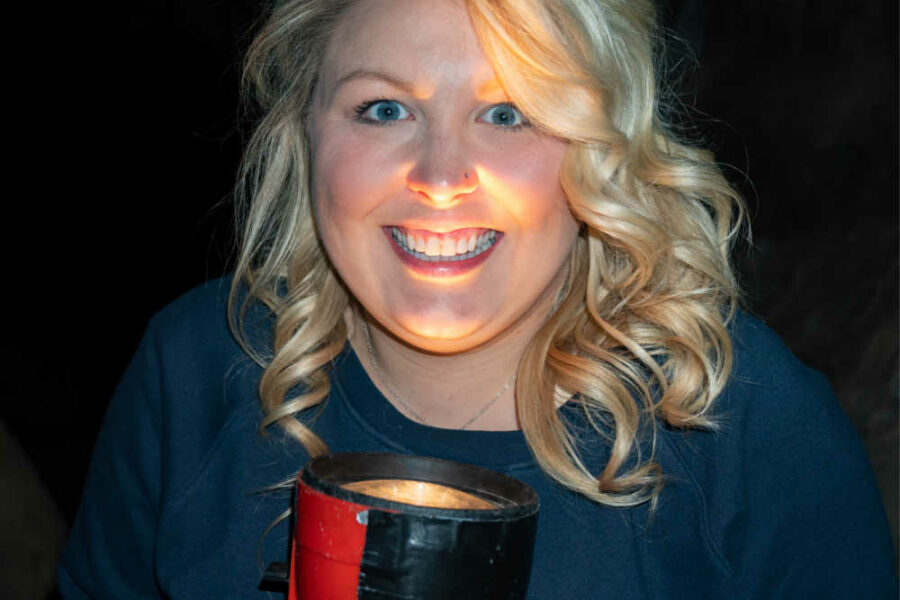 women smiling with flashlight under her chin