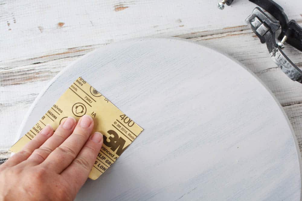 someone sanding a painted round wood circle