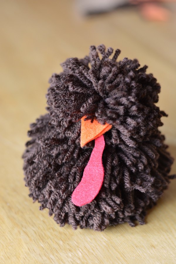 Two brown pom poms with an orange felt beak and red felt turkey throat